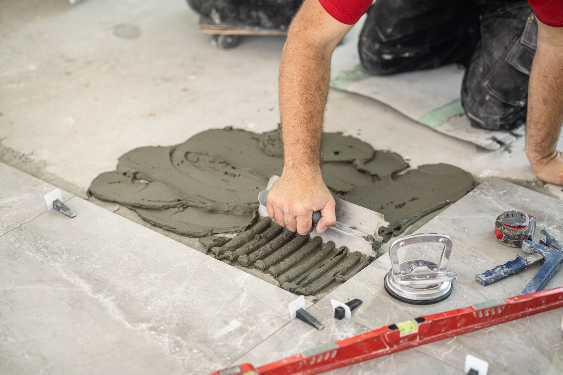 Spreading tile adhesive on the floor